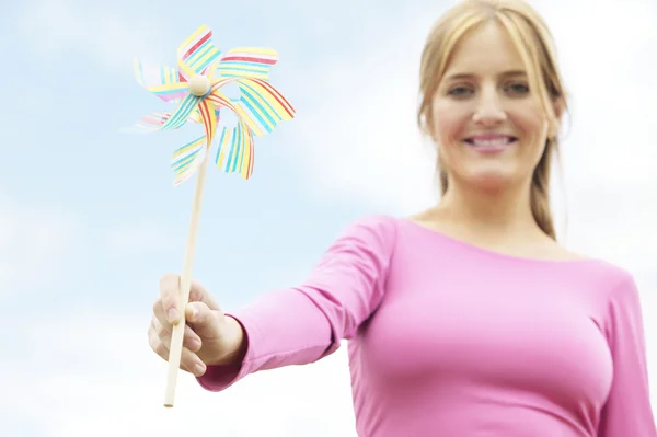 Attractive young woman holidng a small wind mill — Stock Photo, Image