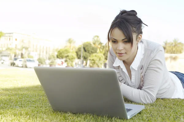 Close up van een jonge vrouw met behulp van een laptop in een park in de stad. — Stockfoto