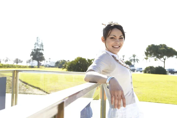 Giovane donna appoggiata a una ringhiera metallica in un parco — Foto Stock