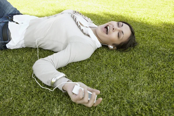 Mujer joven cantando junto a la música que está escuchando con sus auriculares —  Fotos de Stock