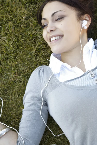 Mujer joven escuchando música en sus auriculares — Foto de Stock