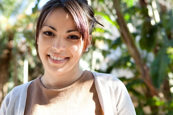 Krásná mladá žena stojící v zeleném parku na slunečný den — Stock fotografie