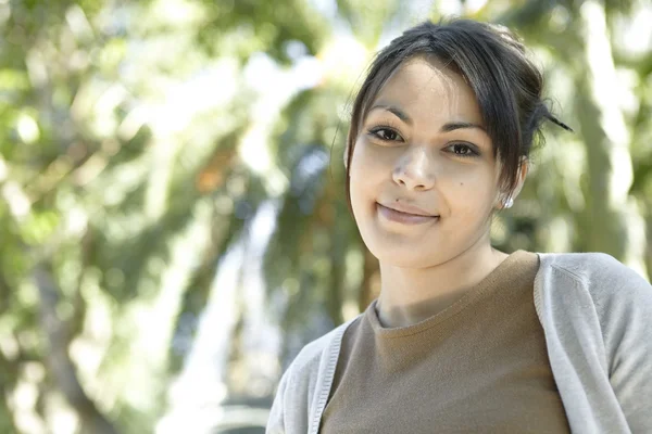 Mujer joven con follaje verde en el fondo . — Foto de Stock