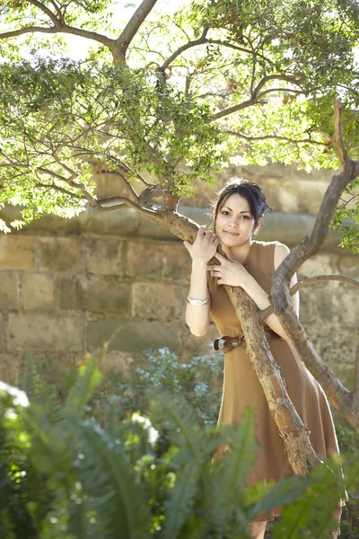 Jolie jeune femme appuyée sur un arbre dans le parc — Photo