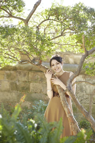 Mujer joven apoyada en un árbol en el parque — Foto de Stock