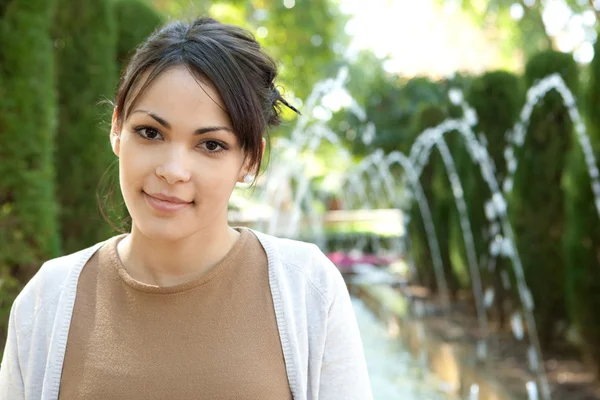 Attractive young tourist woman standing near a fountain — Stock Photo, Image