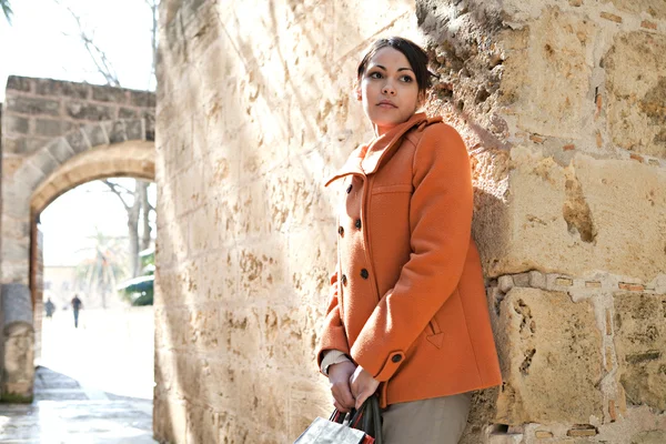 Attraente giovane donna ispanica appoggiata su un vecchio muro di pietra — Foto Stock