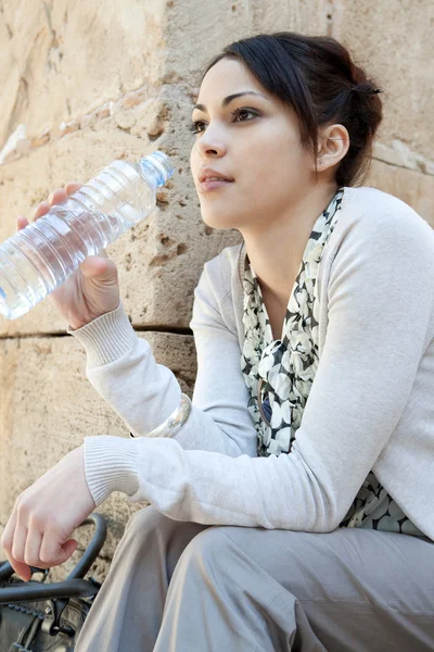 Молодая женщина сливает воду из пластиковой синей бутылки — стоковое фото