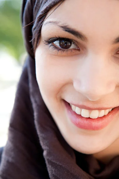 Mujer joven musulmana con una bufanda en la cabeza y sonriendo a la cámara — Foto de Stock