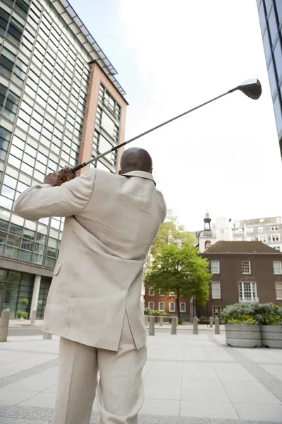 Businessman playing golf in the middle of the financial district. — Stock Photo, Image