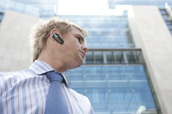 Ung affärsman med en händerna fria enhet att tala i telefon — Stockfoto