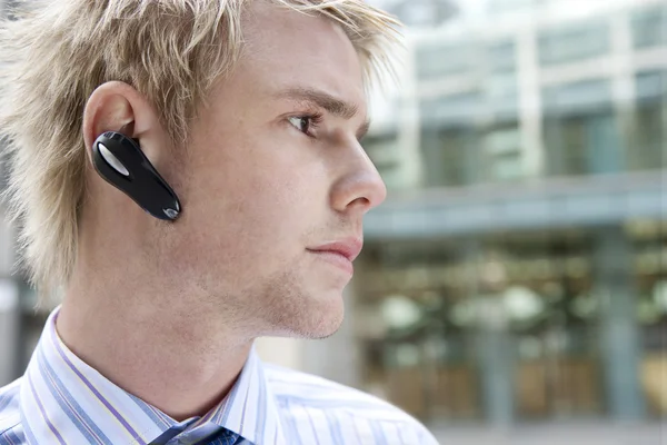 Ung affärsman med en händerna fria enhet att tala i telefon — Stockfoto