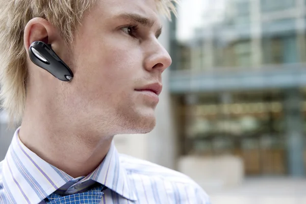 Young businessman using a hands free device to speak on his cell phone — Stock Photo, Image