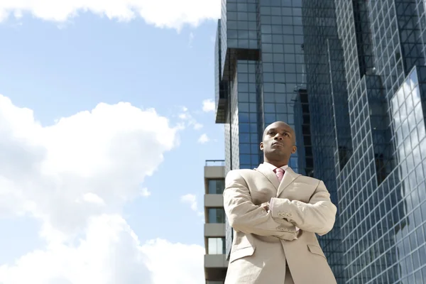 Homme d'affaires debout en toute confiance devant un immeuble de bureaux en verre, à l'extérieur . — Photo