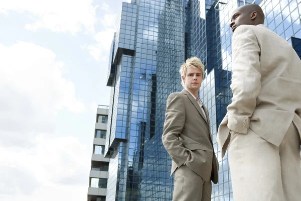 Deux hommes d'affaires debout près d'un immeuble de bureaux moderne . — Photo
