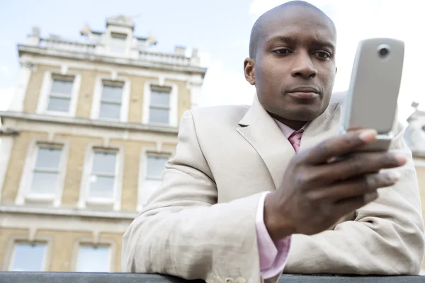 Empresario de mensajes de texto en un teléfono celular al aire libre — Foto de Stock