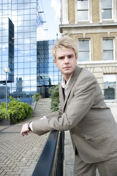 Young businessman leaning on a banister in the city. — Stock Photo, Image