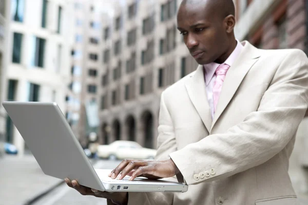 Joven hombre de negocios usando una computadora portátil en el distrito financiero . Imágenes de stock libres de derechos