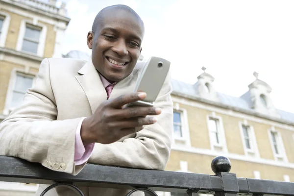 Businessman texting on a cell phone outdoors — Stock Photo, Image