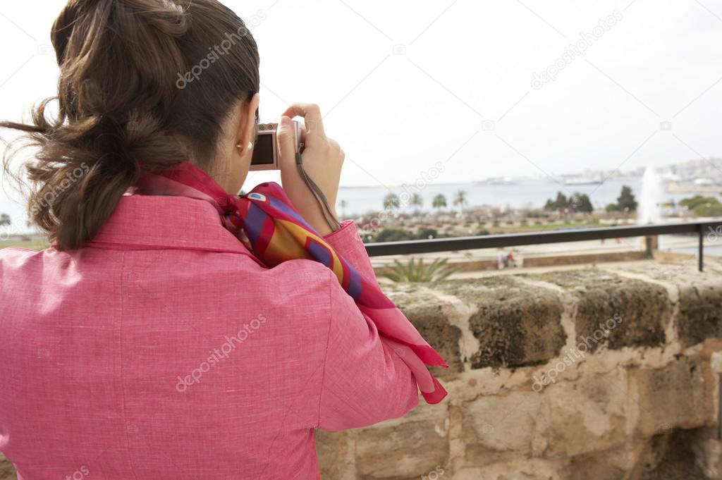 Stylish young woman taking pictures from a city observatory.