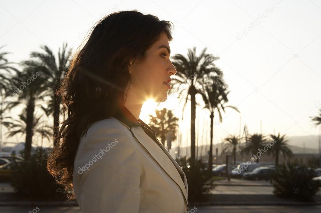 Profile portrait of a woman with sun rays filtering through her neck.