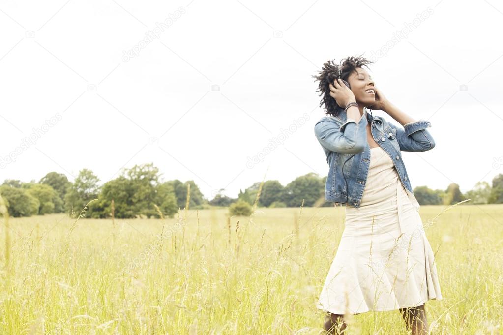 woman listening to music with headphones in an open field