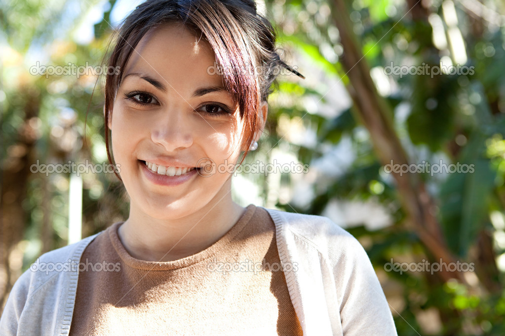 beautiful young woman standing in a green park on a sunny day