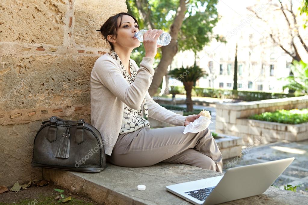 Beautiful young woman having her lunch break in a city park