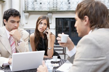 Three business having a meeting at a coffee shop's terrace clipart
