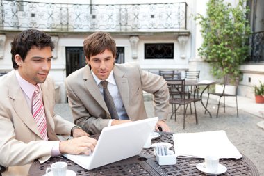 two busy businessmen having a meeting in a coffee shop terrace clipart