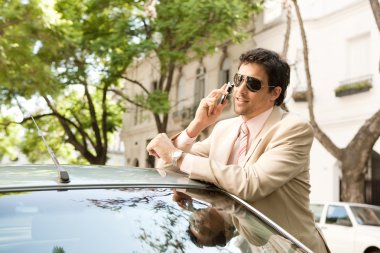 genç işadamı cep telefonundan arabasına yaslanarak süre sohbet