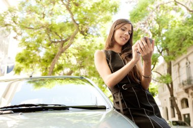 genç çekici işkadını araba yaslanmış iken onun akıllı telefon kullanma