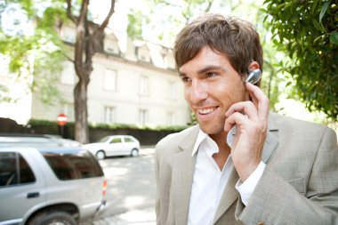 cep telefonuyla konuşmak için bir kulak telefon aygıtı kullanarak çekici genç işadamı