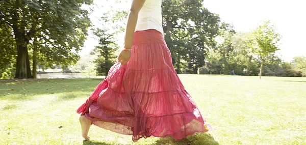 Woman's body section walking across a park — Stock Photo, Image