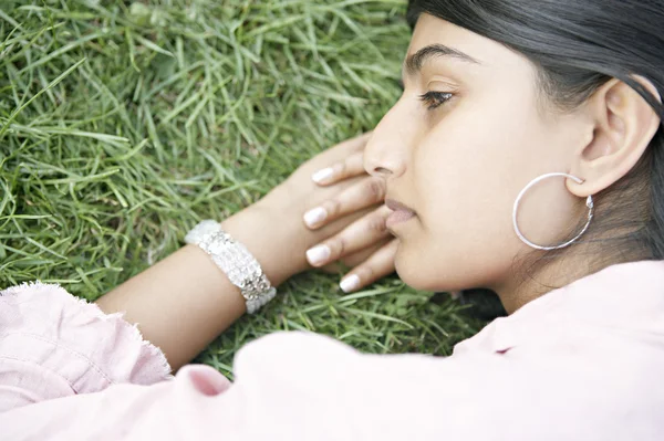 Indiase meisje gezicht vaststelling van op gras. — Stockfoto
