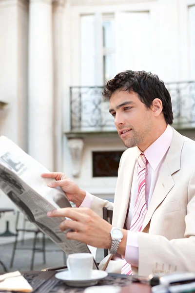 Attractive young businessman reading the newspaper while having breakfast at a coffee shop — Stock Photo, Image