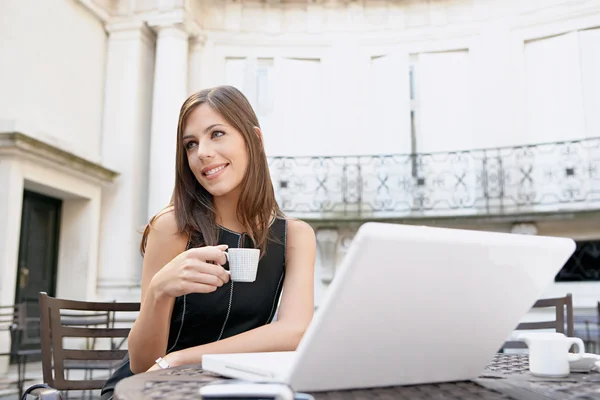 Atractiva empresaria bebiendo café y utilizando una computadora portátil — Foto de Stock