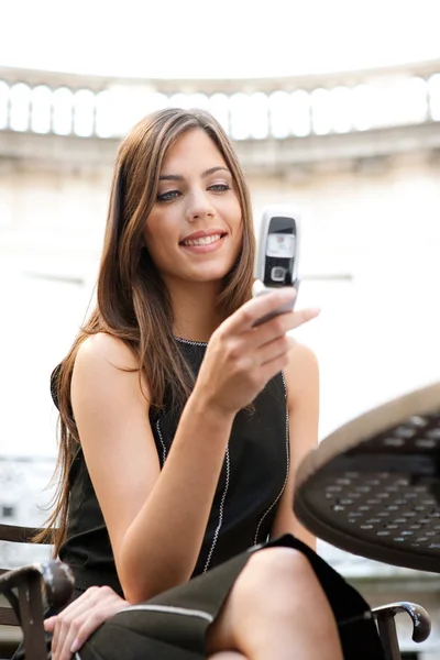 Beautiful businesswoman using a cell phone while sitting in a classic coffee shop — Stock Photo, Image