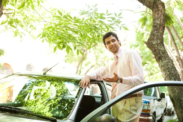 Jovem empresário de sucesso com seu carro tendo uma conversa telefônica usando um mãos livres definido — Fotografia de Stock