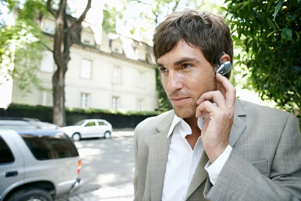 Jeune homme d'affaires utilisant un microphone de pièce d'oreille pour passer un appel téléphonique . — Photo