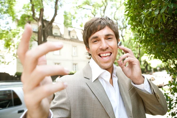 Espressivo giovane uomo d'affari utilizzando un dispositivo auricolare — Foto Stock