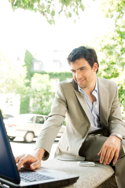 Jovem empresário atraente usando um computador portátil — Fotografia de Stock