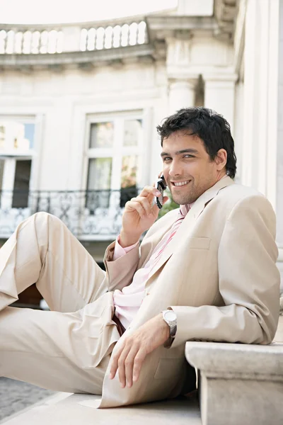 Young attractive businessman smiling and using a cell phone Royalty Free Stock Photos