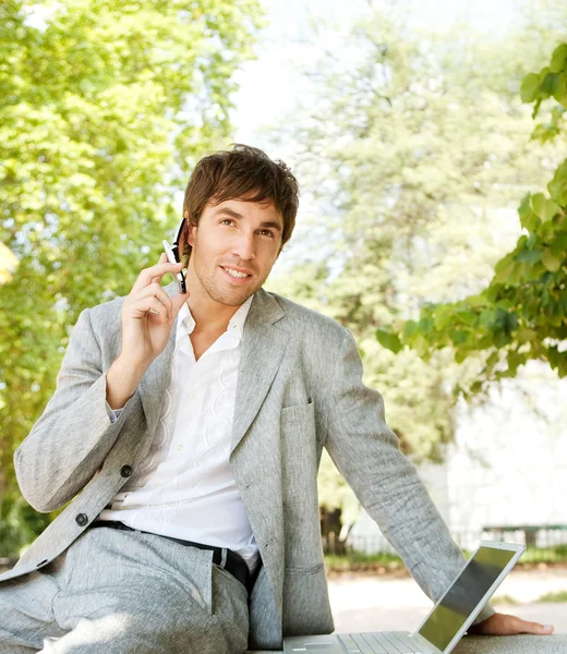 Attractive young businessman using a cell phone and a laptop computer Stock Photo