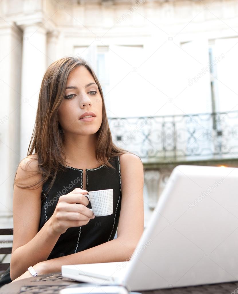 Young attractive businesswoman sitting in a luxurious coffee shop terrace with her laptop