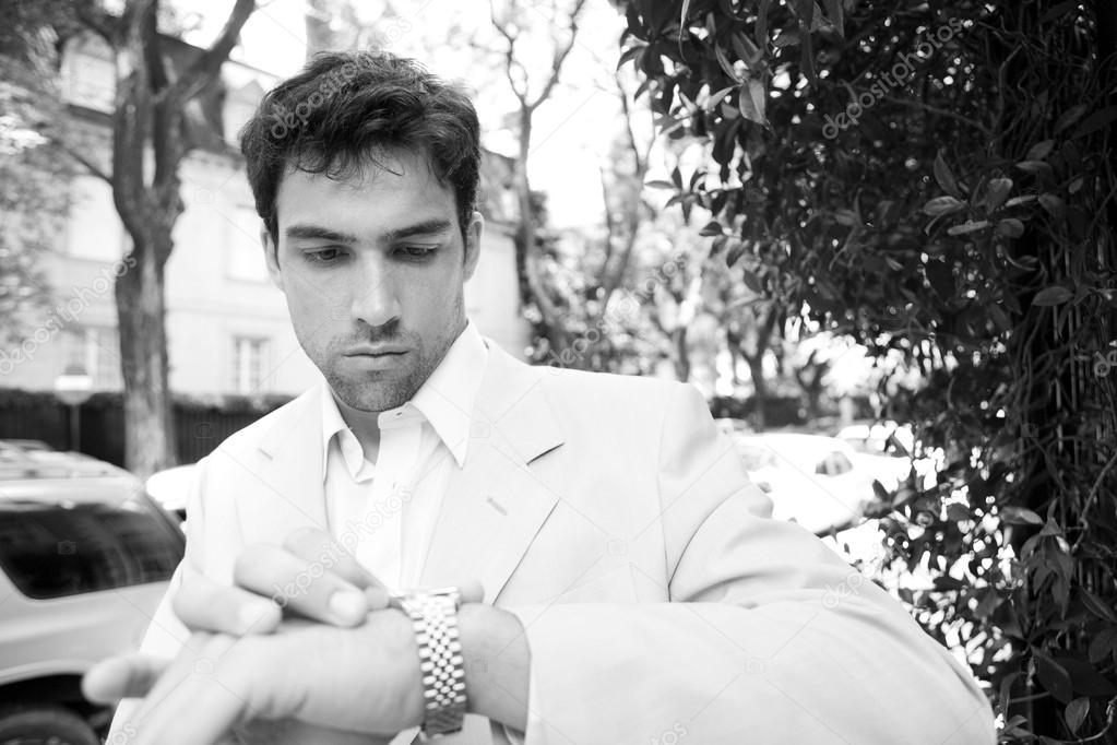 Black and white portrait of a young attractive businessman looking at the time in his watch