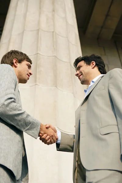 Two young businessmen shaking hands in agreement — Stock Photo, Image