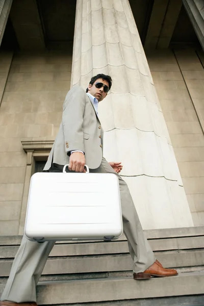 Empresário atraente subindo as escadas de um grande edifício — Fotografia de Stock