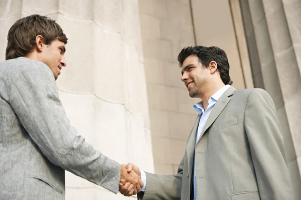 Two young businessmen shaking hands in agreement — Stock Photo, Image