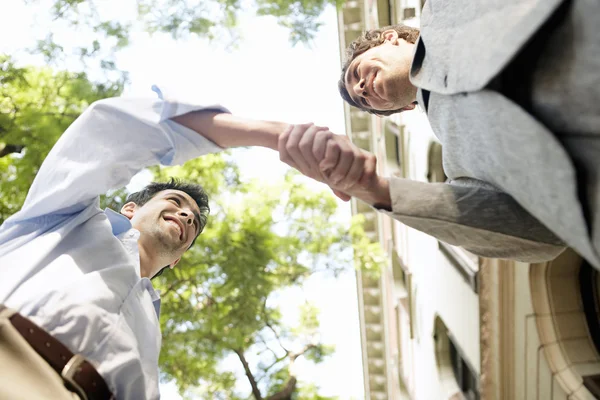 Два бизнесмена пожимают руки в финансовом районе города — стоковое фото